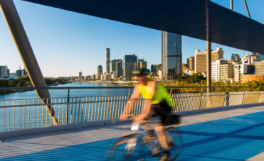 A man riding his bike across a bridge in Brisbane City.